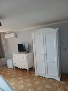 a bedroom with a white cabinet and a television at A Taverna Intru U Vicu in Belmonte Calabro