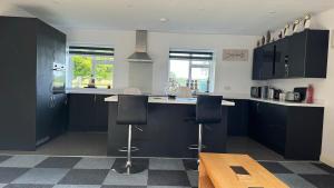 a kitchen with blue cabinets and black counter chairs at Four Poster Hideaway in Chacombe