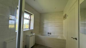 a bathroom with a tub and a sink and a window at Four Poster Hideaway in Chacombe