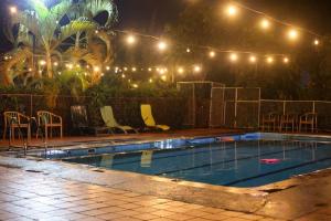 a swimming pool at night with chairs and lights at Cleopatra Gardens in Kampala