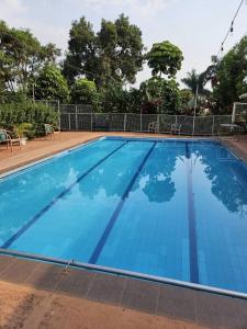 a large blue swimming pool with chairs around it at Cleopatra Gardens in Kampala +8 photos