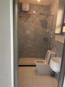 a bathroom with a shower with a toilet and a sink at Cleopatra Gardens in Kampala