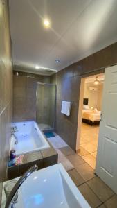 a large bathroom with a tub and a bedroom at The Oasis Guesthouse in Mtubatuba