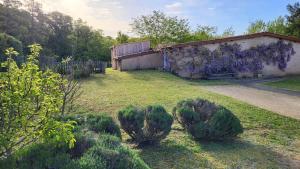 a yard with a building with bushes in the grass at Loveroom in Lavoux