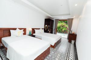 two beds in a room with a window at Champs De Tam Coc Hotel in Vũ Lâm