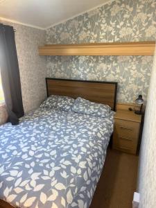 a bedroom with a bed with a blue and white comforter at Seaside Getaways Caravan Hire in Chapel Saint Leonards