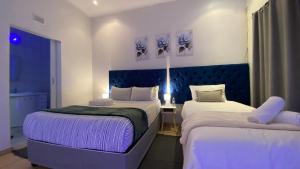 a bedroom with two beds and a blue headboard at The Oasis Guesthouse in Mtubatuba