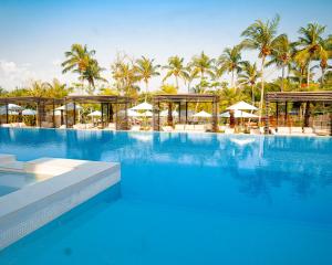 a large swimming pool with palm trees and umbrellas at BBr in Jacqueville