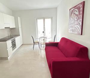a living room with a red couch and a kitchen at Fortezza Apartments in Le Castella +6 photos