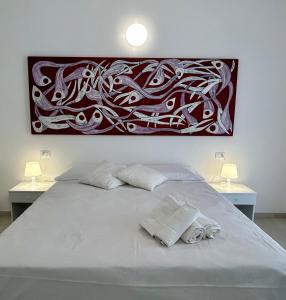 a bedroom with a white bed with a painting on the wall at Fortezza Apartments in Le Castella