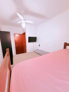 a bedroom with two beds and a ceiling fan at Apartamento Mirim Praia Grande in Praia Grande