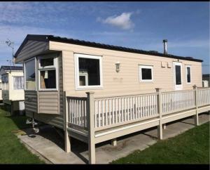 a tiny house on a trailer in a yard at Seaside Getaways Caravan Hire in Chapel Saint Leonards