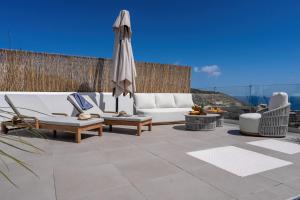 a patio with chairs and an umbrella and a couch at villa yasmin luxury in Bali