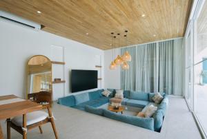 a living room with a blue couch and a television at The Avlu Modern Spa Retreat in Tanah Lot