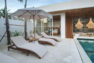 a patio with chairs and an umbrella and a pool at The Avlu Modern Spa Retreat in Tanah Lot