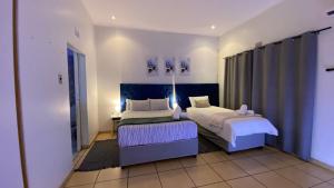 a bedroom with two beds and a blue headboard at The Oasis Guesthouse in Mtubatuba