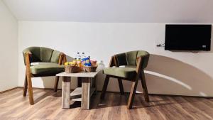 two chairs and a table with a tv on a wall at The Forest Castle Resort in Pahalgām