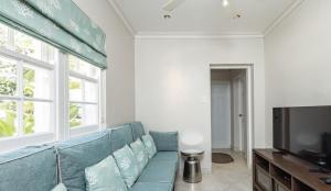 a living room with a blue couch and a television at Royal Westmoreland Lonetrees - by ZenBreak in Saint James