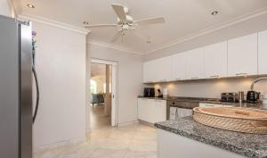 a kitchen with white cabinets and a ceiling fan at Royal Westmoreland Lonetrees - by ZenBreak in Saint James