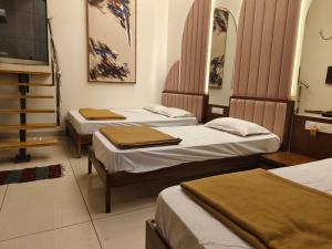 a room with three beds and a television at Agatya Homestay in Kolhapur