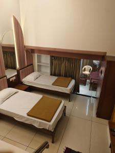 a room with two beds and a chair in it at Agatya Homestay in Kolhapur