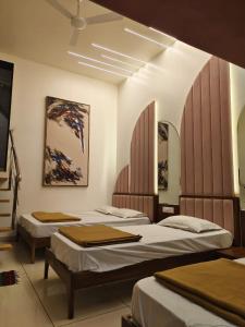 a room with three beds and two mirrors at Agatya Homestay in Kolhapur