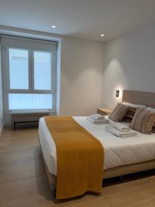 a bedroom with a large bed and a window at Apartamentos DORRE LUZEA Apartamentuak in Zarautz