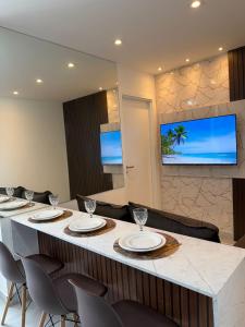 a restaurant with a long counter with chairs and a television at Apartamento Novo Infinity in Vila Velha