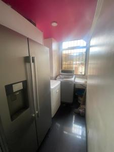 a small kitchen with a pink ceiling and a refrigerator at Casa Cristian in Caracas