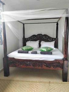 a wooden bed with green and white pillows on it at Diani Hideaway Beach Villa, private pool, air conditioning and WiFi in Galu +104 photos
