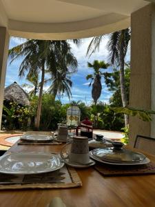 a table with plates on it with a view of the ocean at Diani Hideaway Beach Villa, private pool, air conditioning and WiFi in Galu