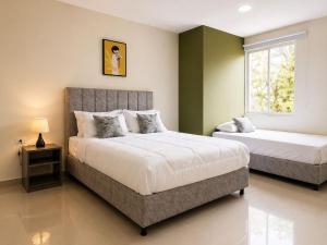a bedroom with two beds and a window at Fuscaldo Hotel in Valledupar