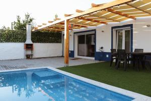 a house with a swimming pool and a wooden pergola at Páteo da Chica in Cano