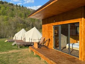 a group of three tents with a bed and a table at Glamping - Casuta Zen Fiad in Romuli +9 photos