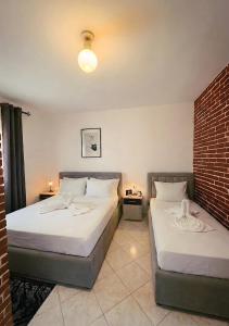 a bedroom with two beds and a brick wall at Villa Murataj in Ksamil