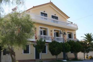 a large yellow house with trees in front of it at Karyatis studios lixouri in Lixouri