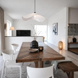 a dining room with a wooden table and white chairs at Vila Karup Modern Scandinavian Holiday Home in Båstad +18 photos