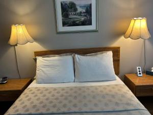 a bedroom with a bed with pillows and two lamps at Motel Casino in Gatineau