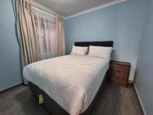 a bedroom with a large bed with white sheets and a window at Masakwe BNB in Soweto