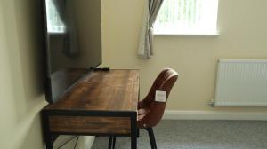 a wooden table with a chair and a desk at Easy living stays Burton on Trent in Burton upon Trent +2 photos