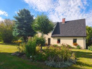 a white house with a black roof and a garden at Agroturystyka Pod Leszczyną in Wambierzyce