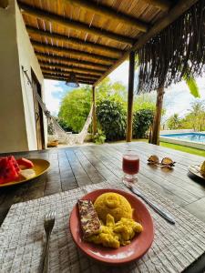 a plate of food on a table with a glass of wine at Pousada Vila do Alto in Japaratinga