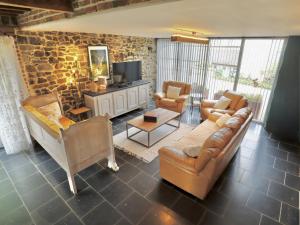 a living room with a couch and chairs and a tv at Le Grenier de Louise in Gimnée