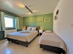 two beds in a bedroom with green walls at Le Grenier de Louise in Gimnée