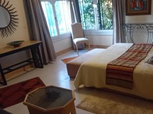 a bedroom with a bed and a table and a chair at Le havre de paix in Marrakesh