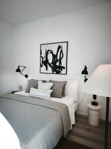 a white bedroom with a bed and two lamps at Vila Karup Modern Scandinavian Holiday Home in Båstad
