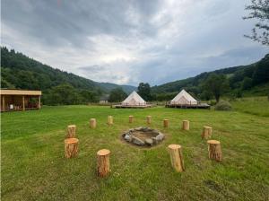 a field with tents and logs in the grass at Glamping - Casuta Zen Fiad in Romuli