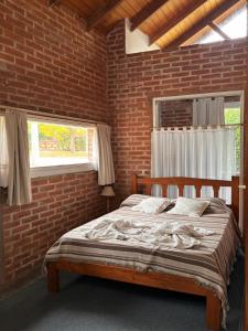 a bedroom with a wooden bed in a brick wall at Complejo Aldea Champaqui in Villa General Belgrano