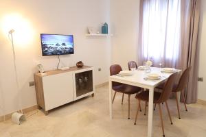 a dining room with a white table and a tv at Puerta de Arcos in Arcos de la Frontera