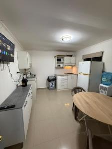 a small kitchen with a table and a refrigerator at Casa Hostal , Mejillones in Mejillones
